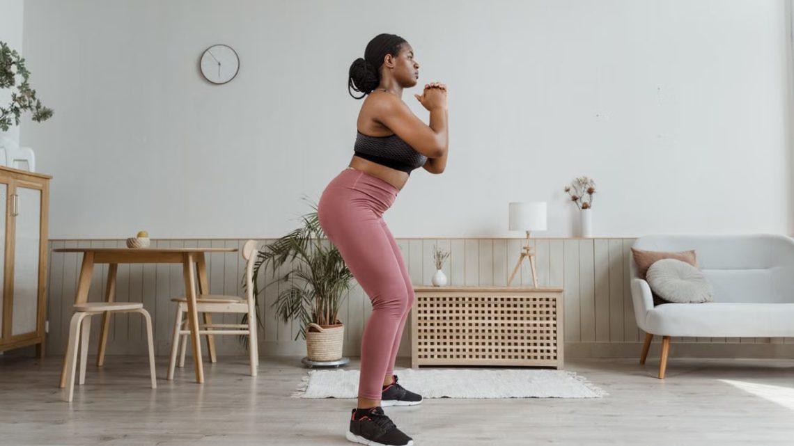 Black woman exercising at home in stylish activewear, promoting a healthy lifestyle.